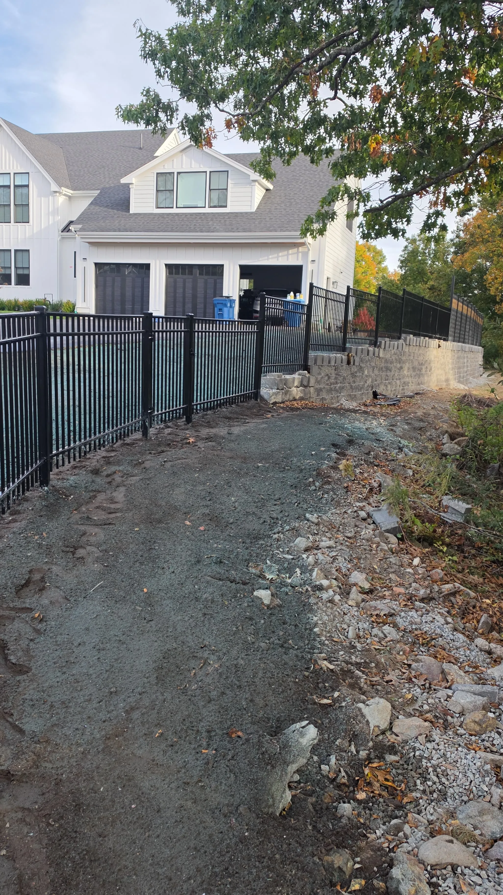 Black metal fence installed along the top of a retaining wall in Massachusetts