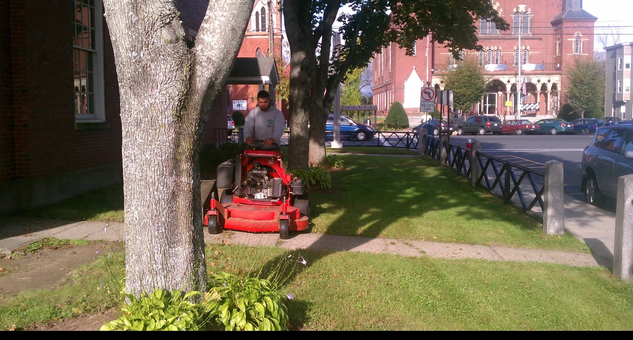 Crew member mowing a commercial lawn with a walk-behind mower in Massachusetts