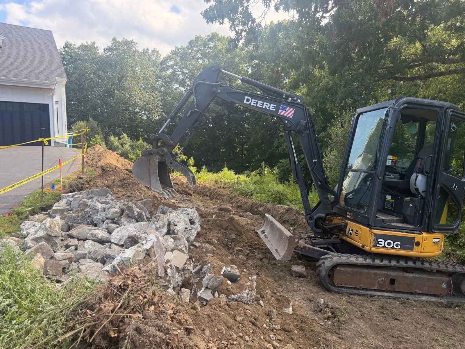 Mini excavator removing concrete during site excavation in Massachusetts