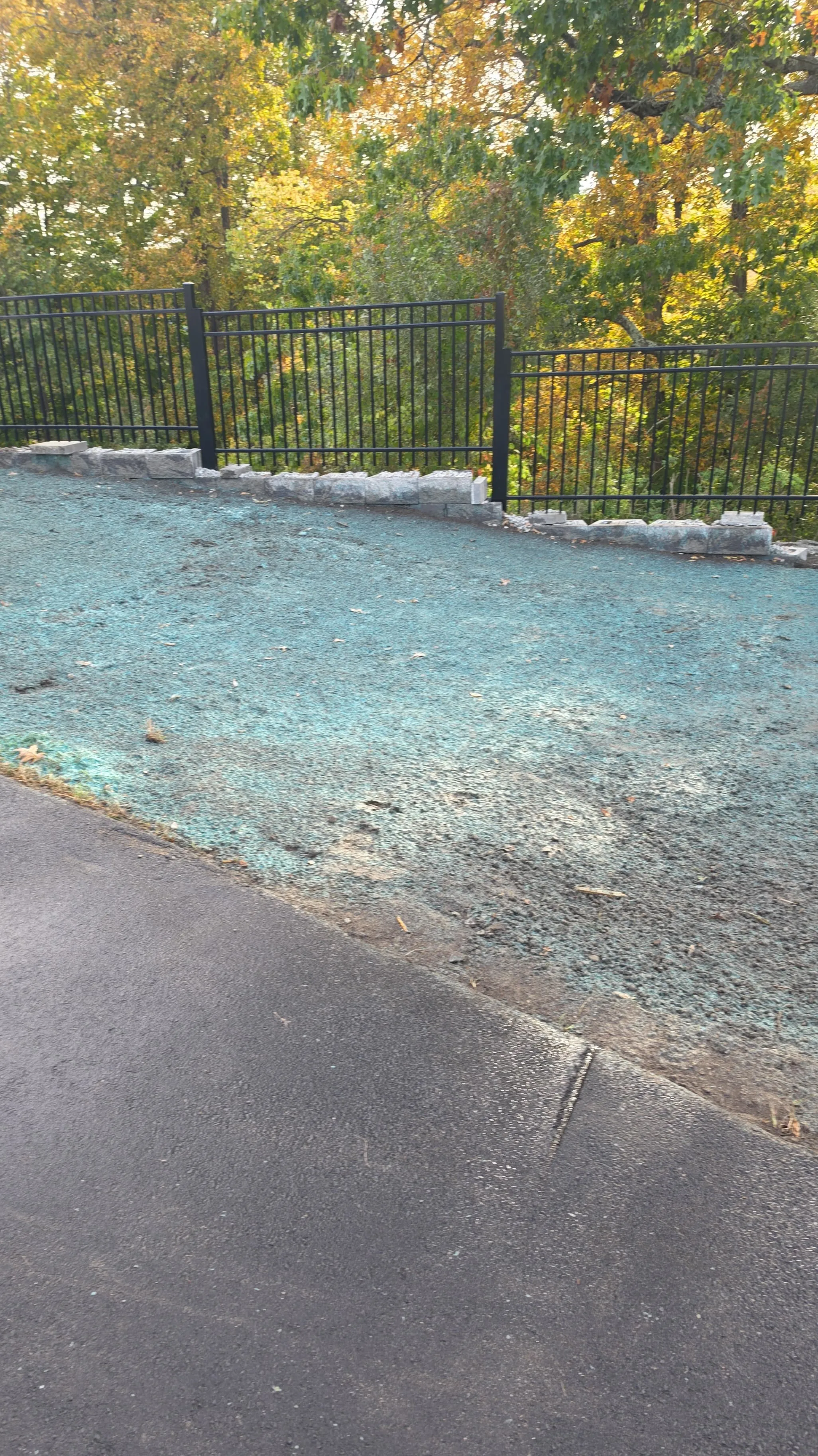 Hydroseeded slope below stone edging and a black metal fence in Massachusetts