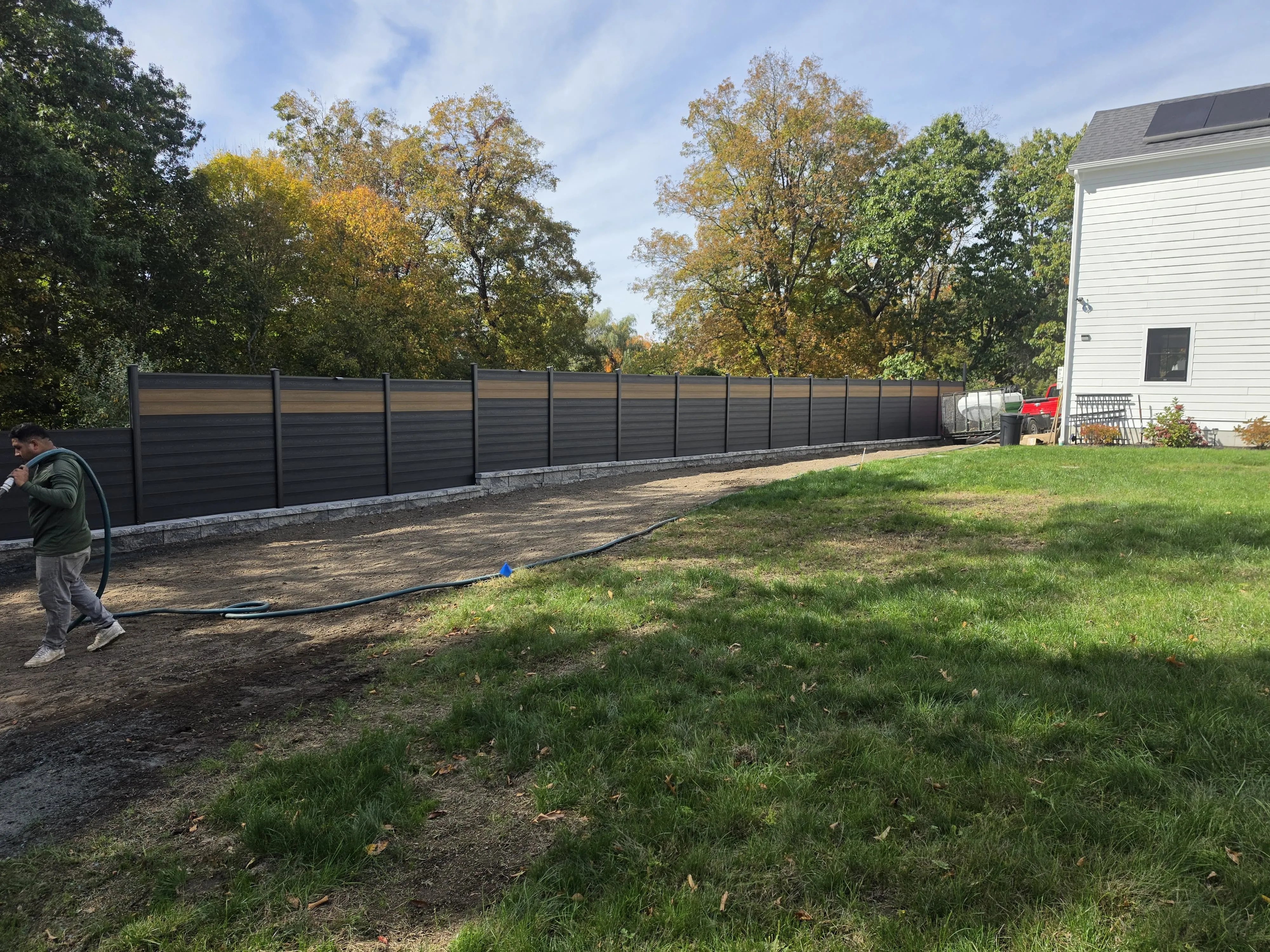 Graded soil prepared for a new lawn along a new privacy fence in Massachusetts