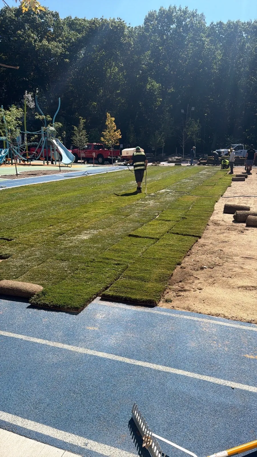 Crew laying sod rolls on an athletic field in Boston, MA